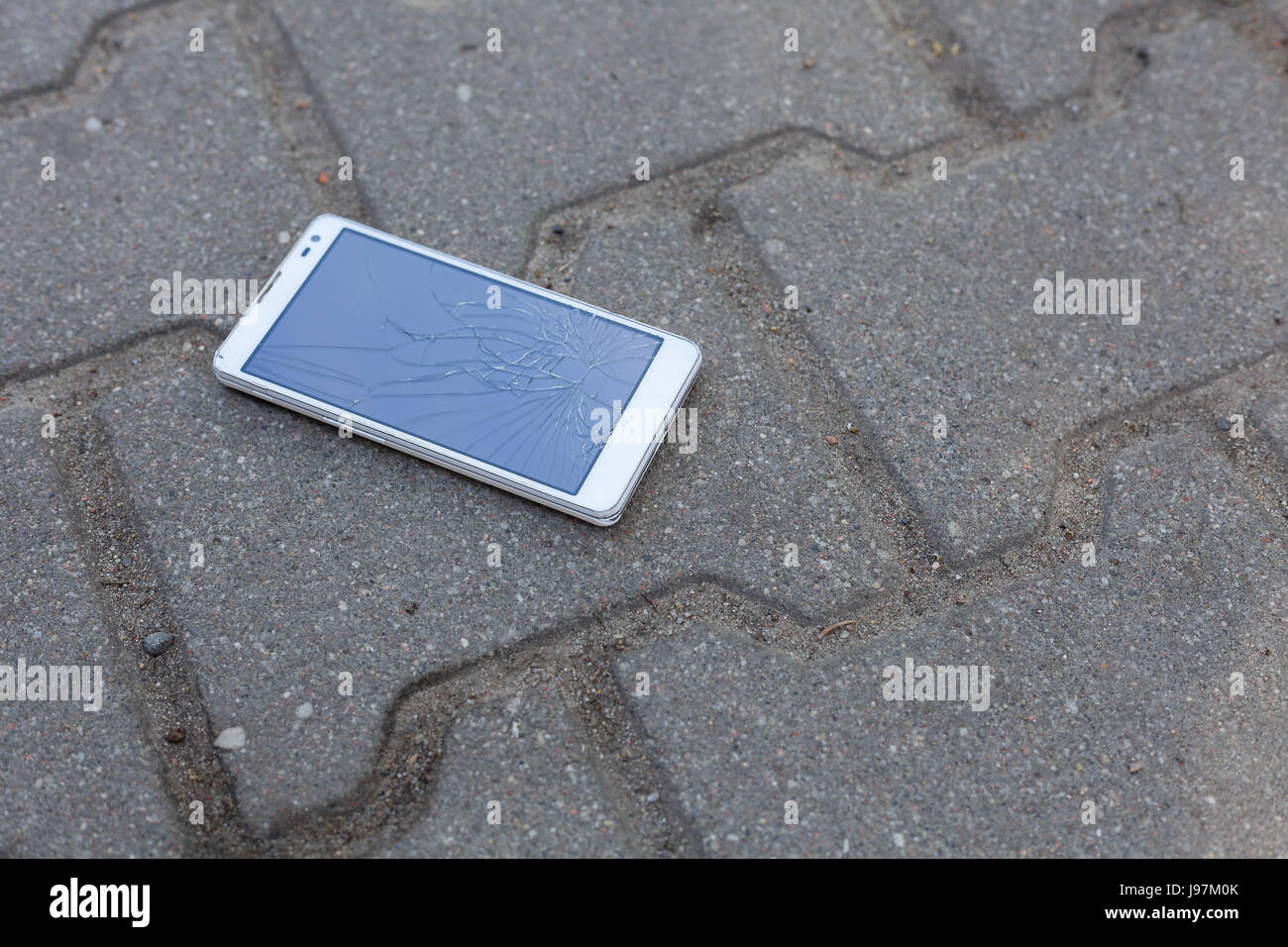 Téléphone avec écran brisé gisant sur le trottoir Banque D'Images