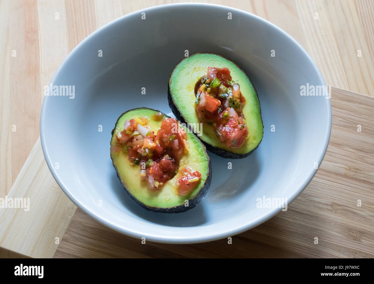 L'avocat et la salsa fresca dans un petit bol blanc sur une table en bois Banque D'Images