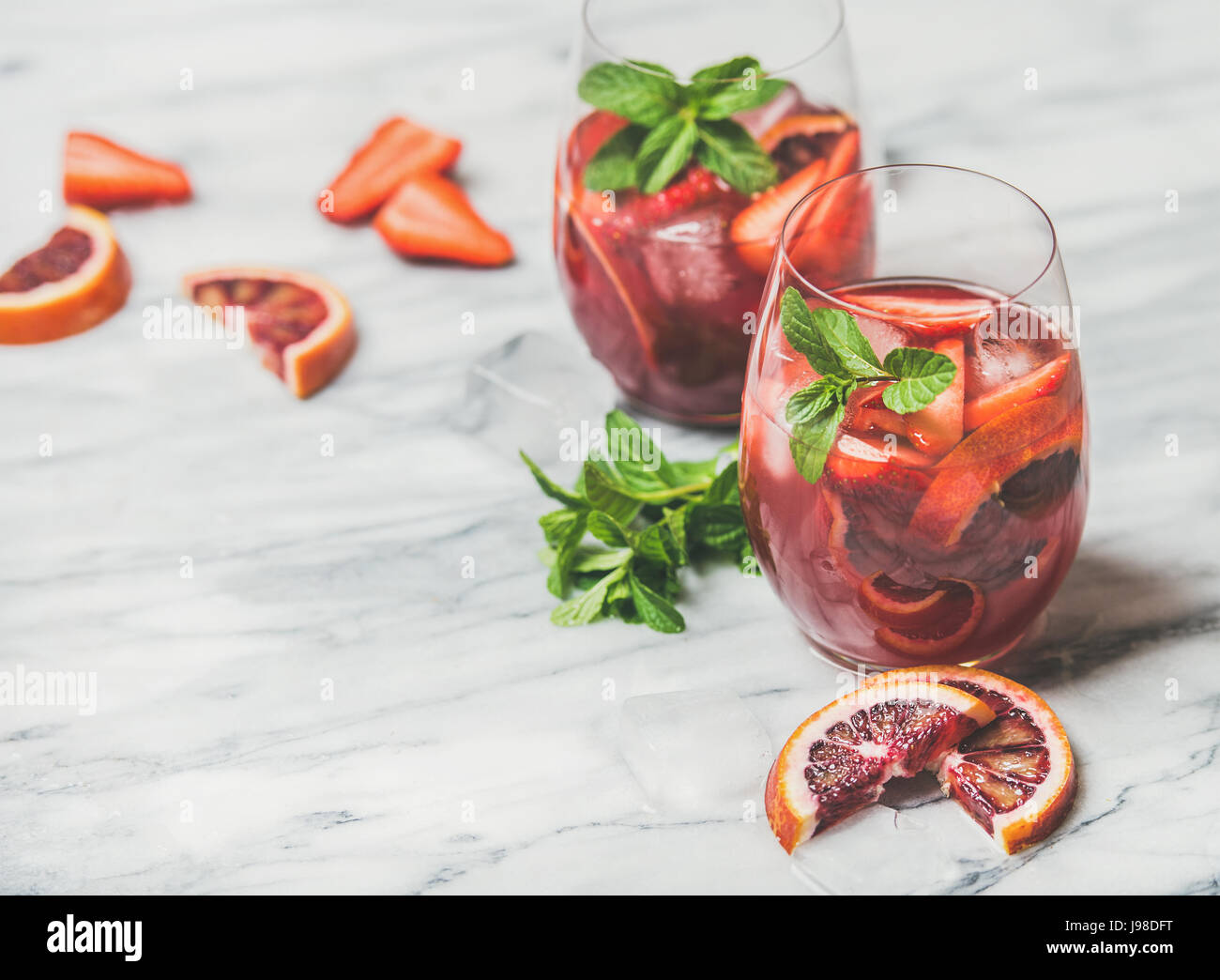 Des cocktails de fruits Sangria rafraîchissante avec des cubes de glace et de menthe fraîche Banque D'Images