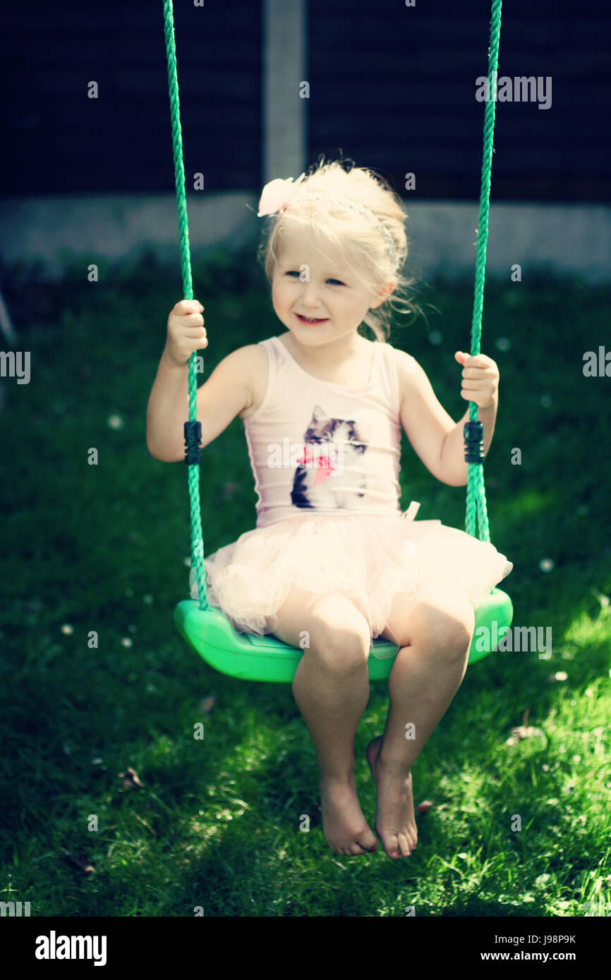 L'enfant blond kid tutu oscillante swing l'été le jardin, de l'enfance, de la liberté, concept sans soucis, temps heureux, le temps de sa vie, la joie, heureux concept Banque D'Images