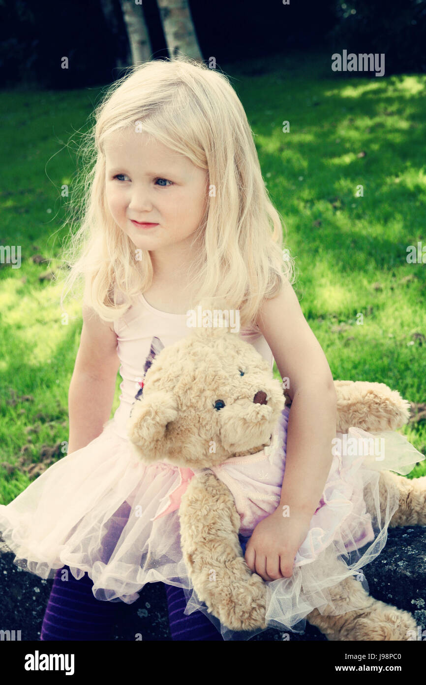 Petite fille de trois ans, enfant long cheveux bouclés blond mur assis,  ours en peluche assorti portant un tutu, innocent concept teddy amour fille  d'enfance Photo Stock - Alamy