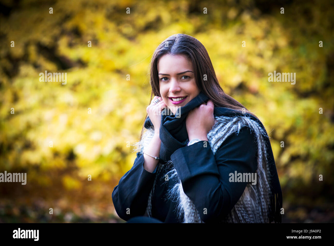 Jeune femme admirant les couleurs chaudes de l'automne dans les bois entourée d'arbres et de laisser d'érable canadien érables acer Japonais, les tons de rouge, orange Banque D'Images