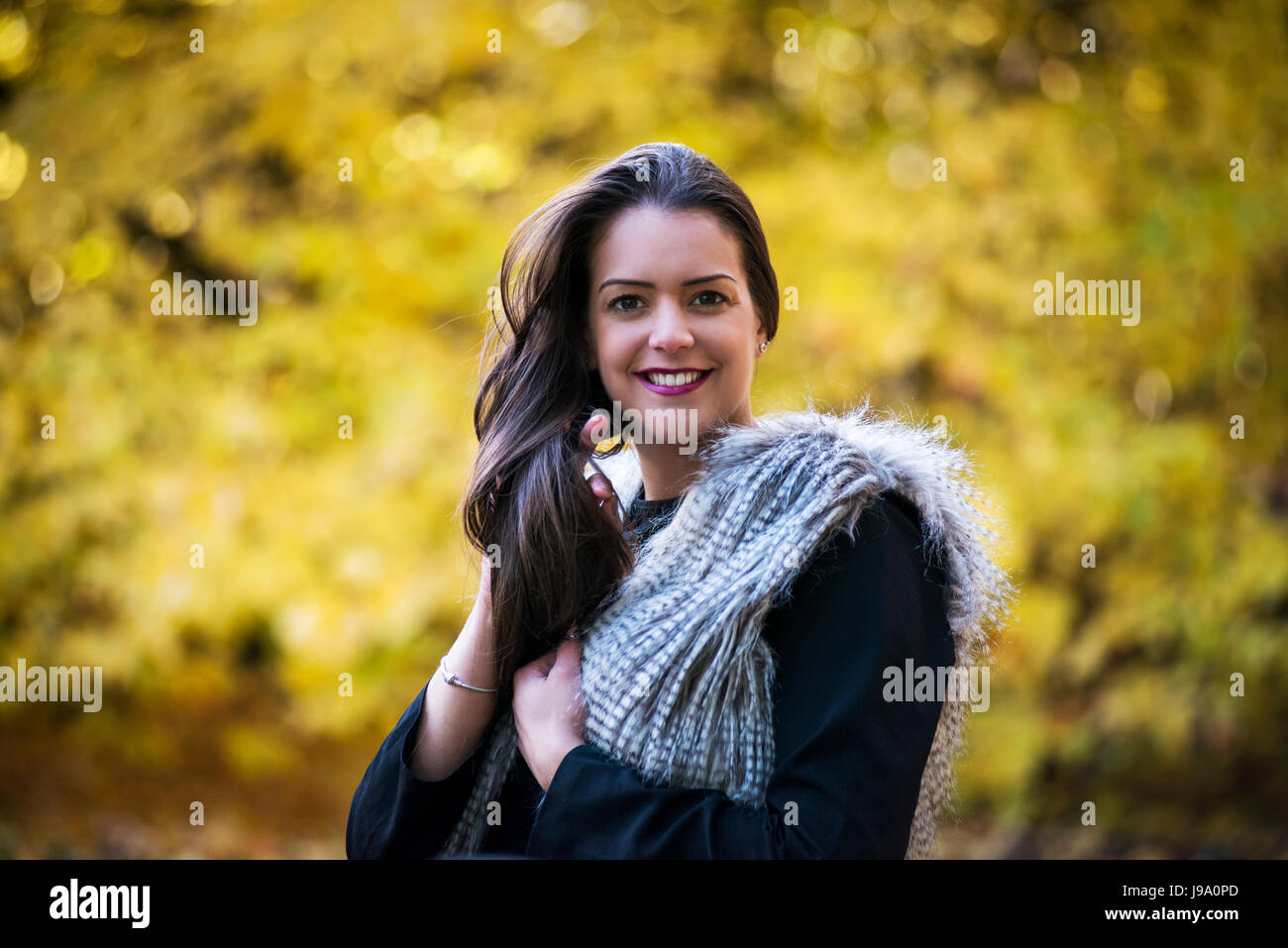 Jeune femme admirant les couleurs chaudes de l'automne dans les bois entourée d'arbres et de laisser d'érable canadien érables acer Japonais, les tons de rouge, orange Banque D'Images