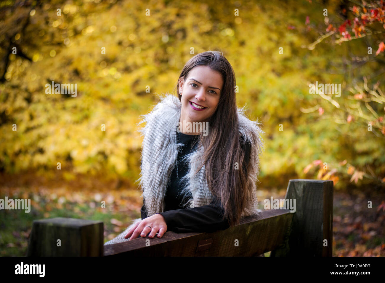 Jeune femme admirant les couleurs chaudes de l'automne dans les bois entourée d'arbres et de laisser d'érable canadien érables acer Japonais, les tons de rouge, orange Banque D'Images