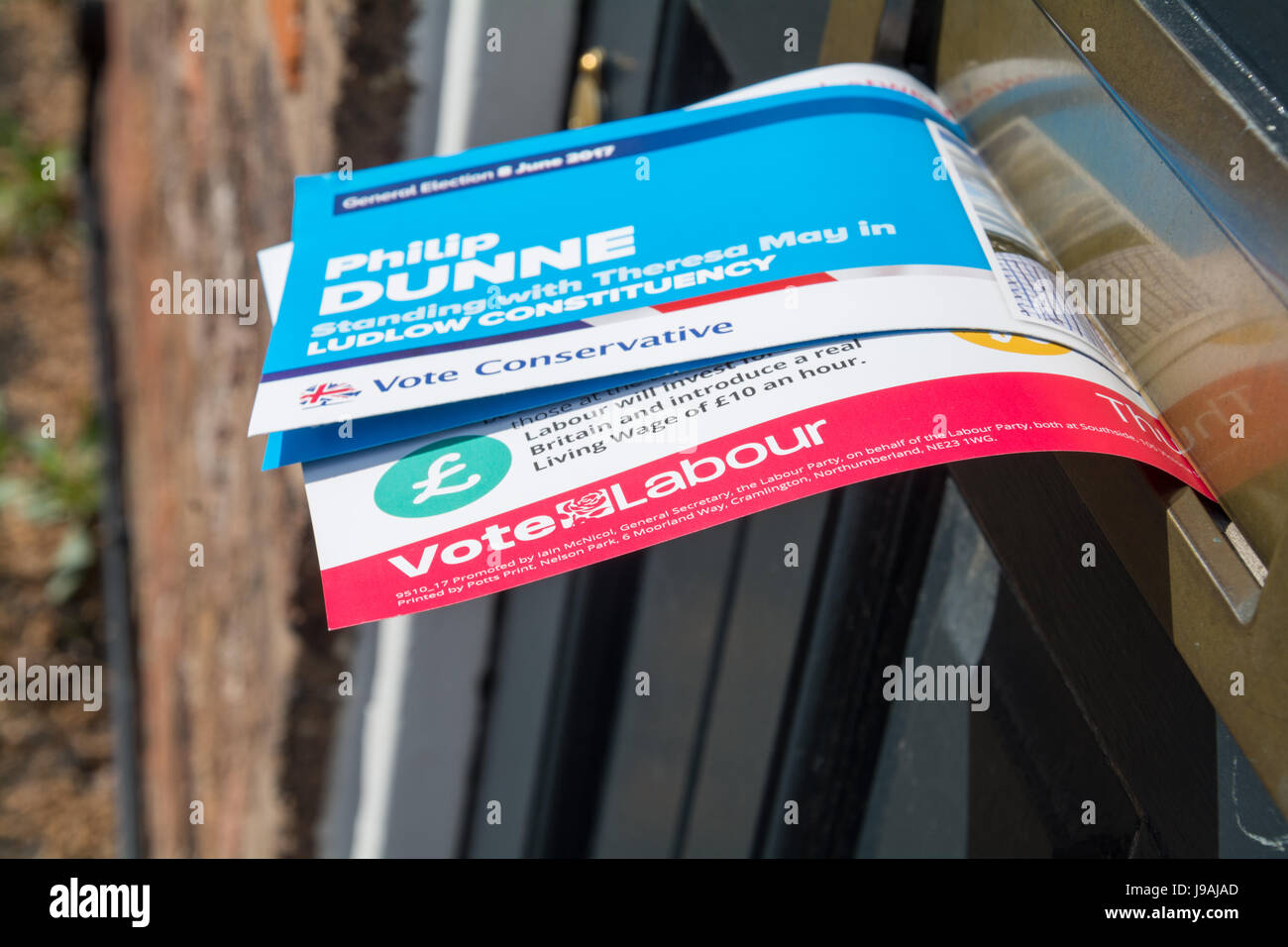 Élection générale de 2017 au Royaume-Uni. Des tracts de campagne pour le parti conservateur et le parti du travail qui sort d'une boîte à lettres. Banque D'Images