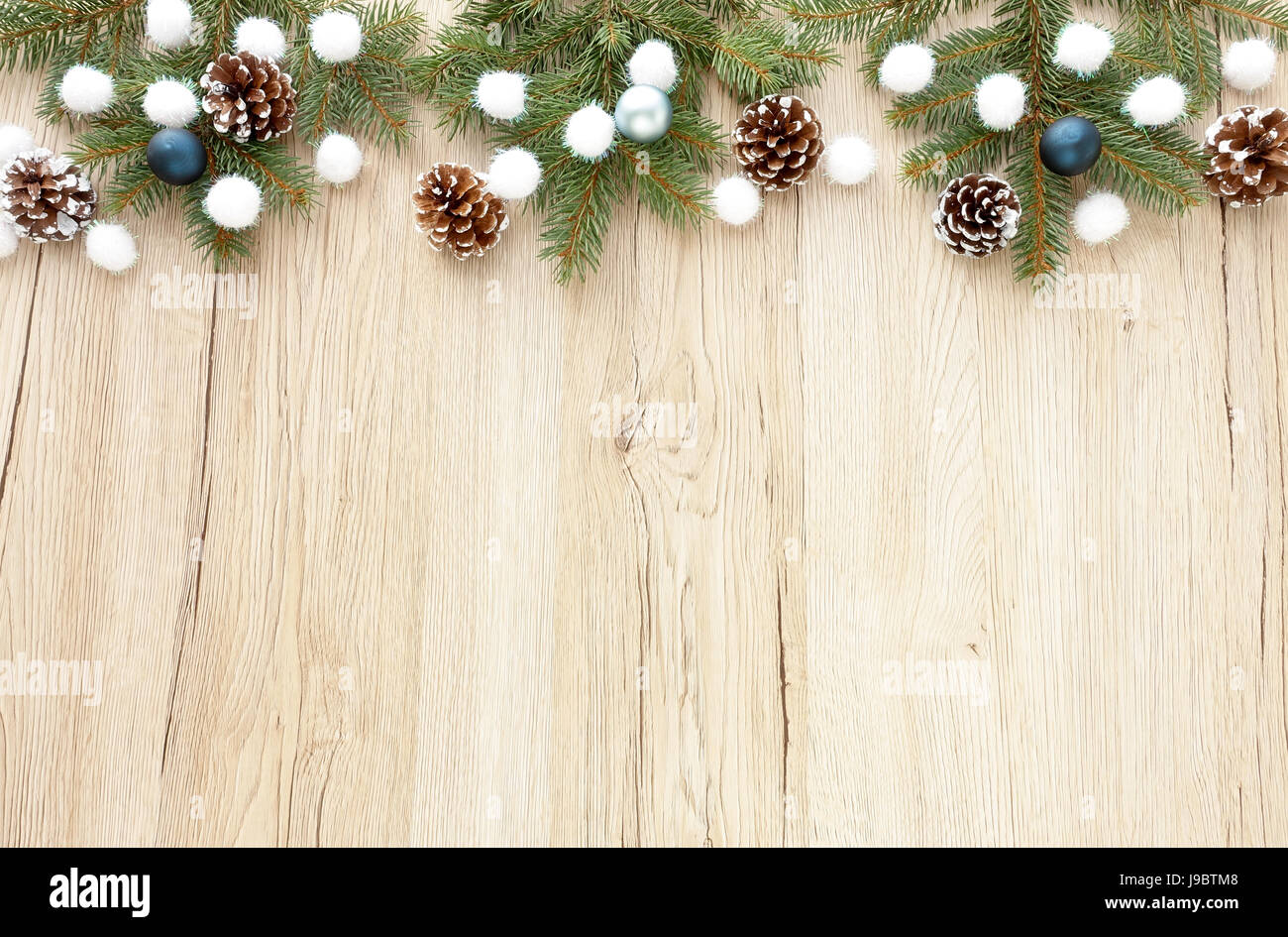 Hors de la frontière de noël sapin enneigé des brindilles, des pommes de pin et des boules de Noël blanc paillettes sur fond en bois brun avec beaucoup d'espace de copie. Banque D'Images