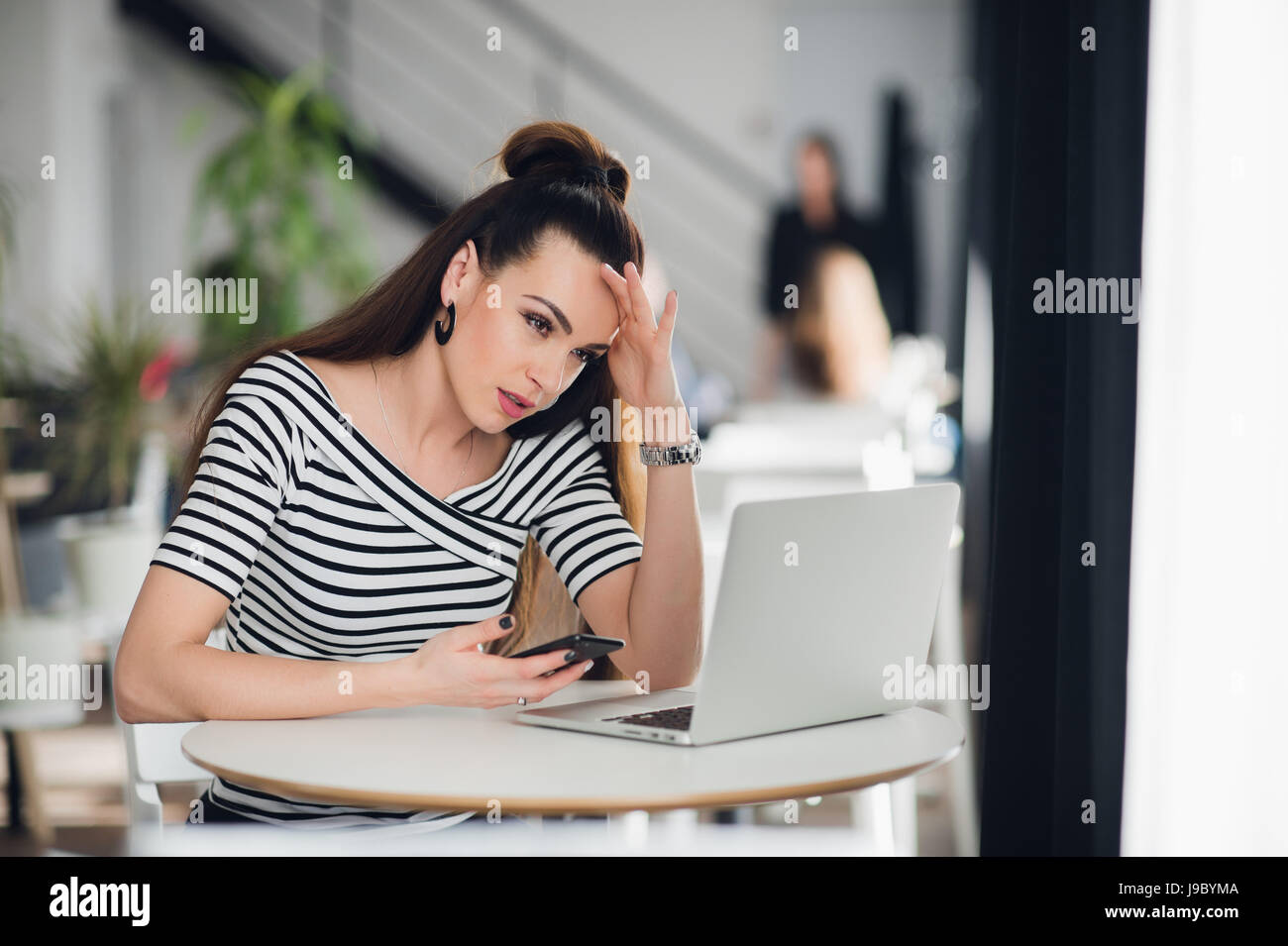 Femme journaliste talentueux pensif attrayant est la réflexion sur des solutions créatives pour faire de l'article travailler dans un café, charmant designer qualifiés de noter des idées pour démarrer en son smartphone. Banque D'Images