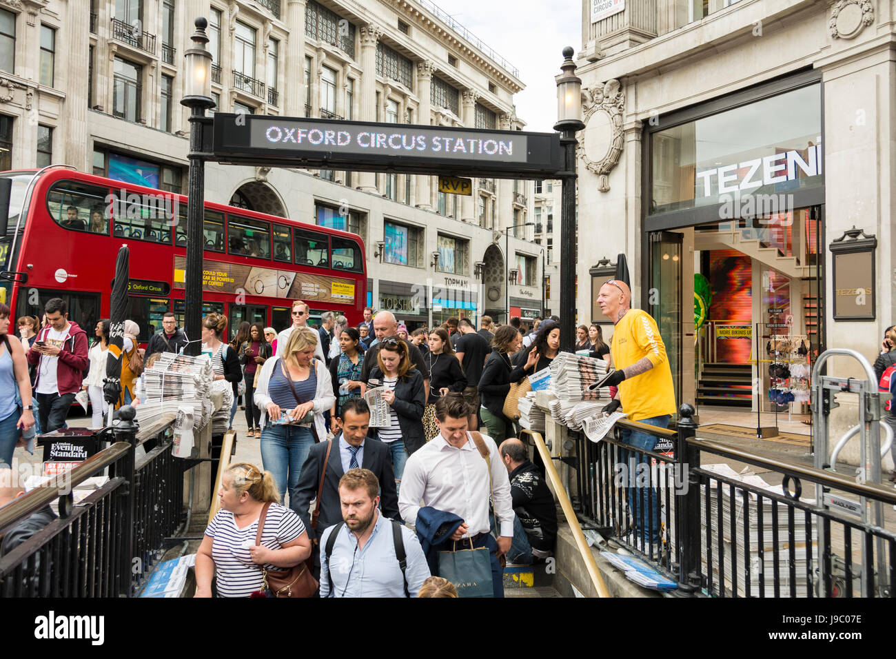 Un fournisseur de journaux Standard de soirée très animé entouré de navetteurs à la station de métro Oxford Circus, Londres, Angleterre, Royaume-Uni Banque D'Images