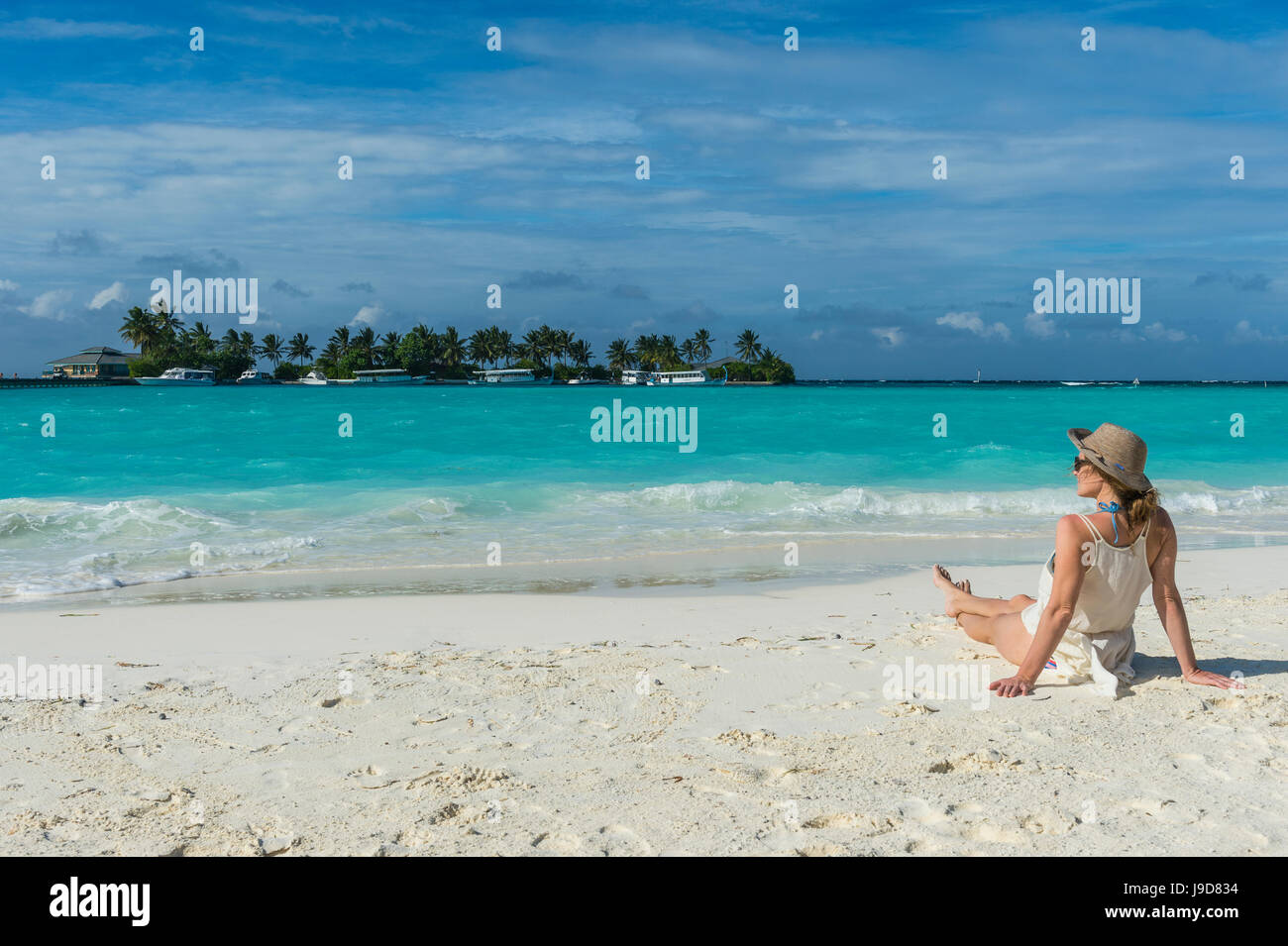 Femme assise sur une plage de sable blanc, eau turquoise le Sun Island Resort, l'île de Dhiffushi, Ari atoll, Maldives Banque D'Images Femme assise sur une plage de sable blanc, eau turquoise le Sun Island Resort, l'île de Dhiffushi, Ari atoll, Maldives Banque D'Images