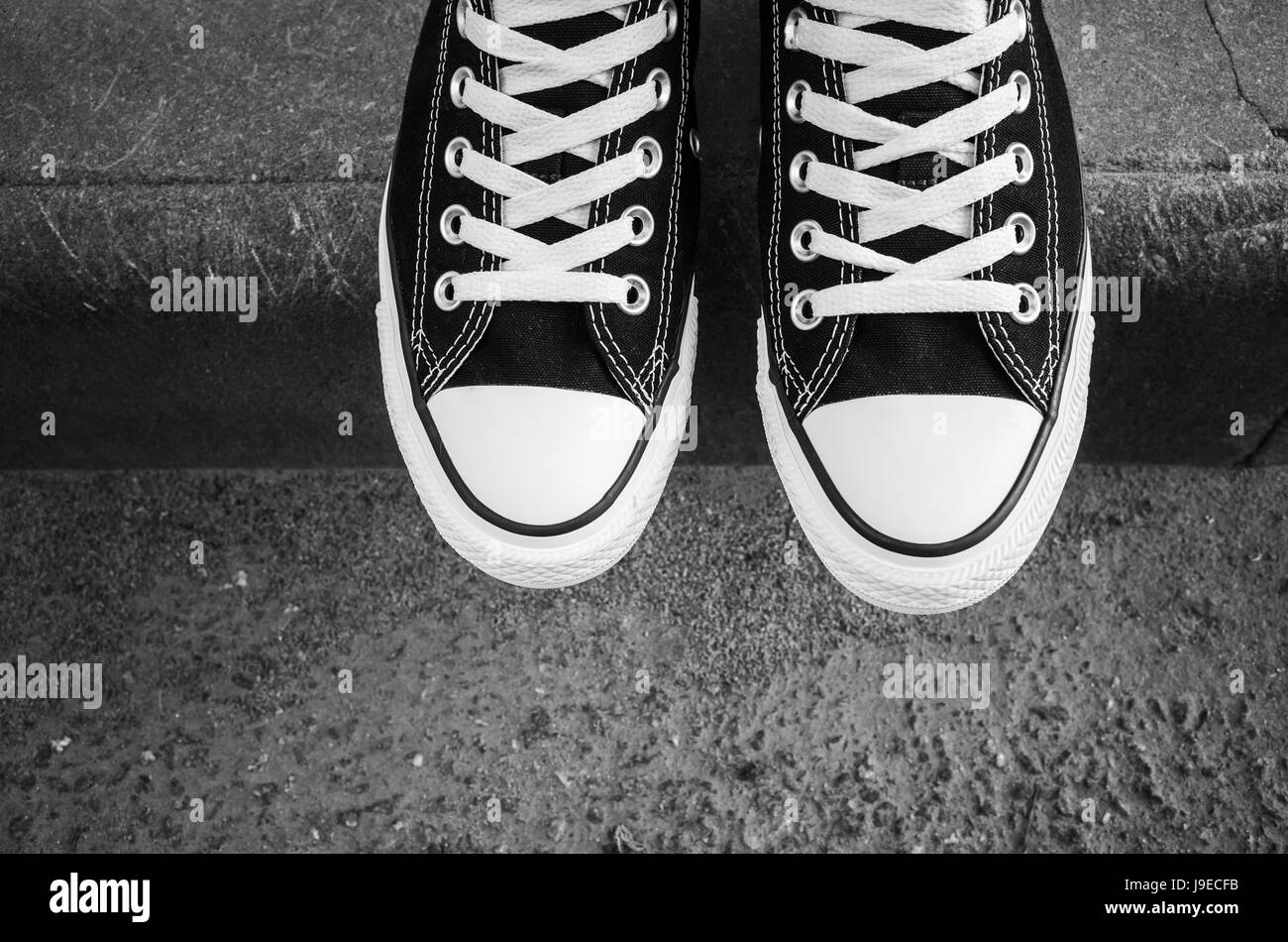 Le noir et blanc nouvelles sneakers, adolescent pieds debout sur la frontière routier urbain. vue d'en haut. Photo Gros Plan avec selective focus Banque D'Images