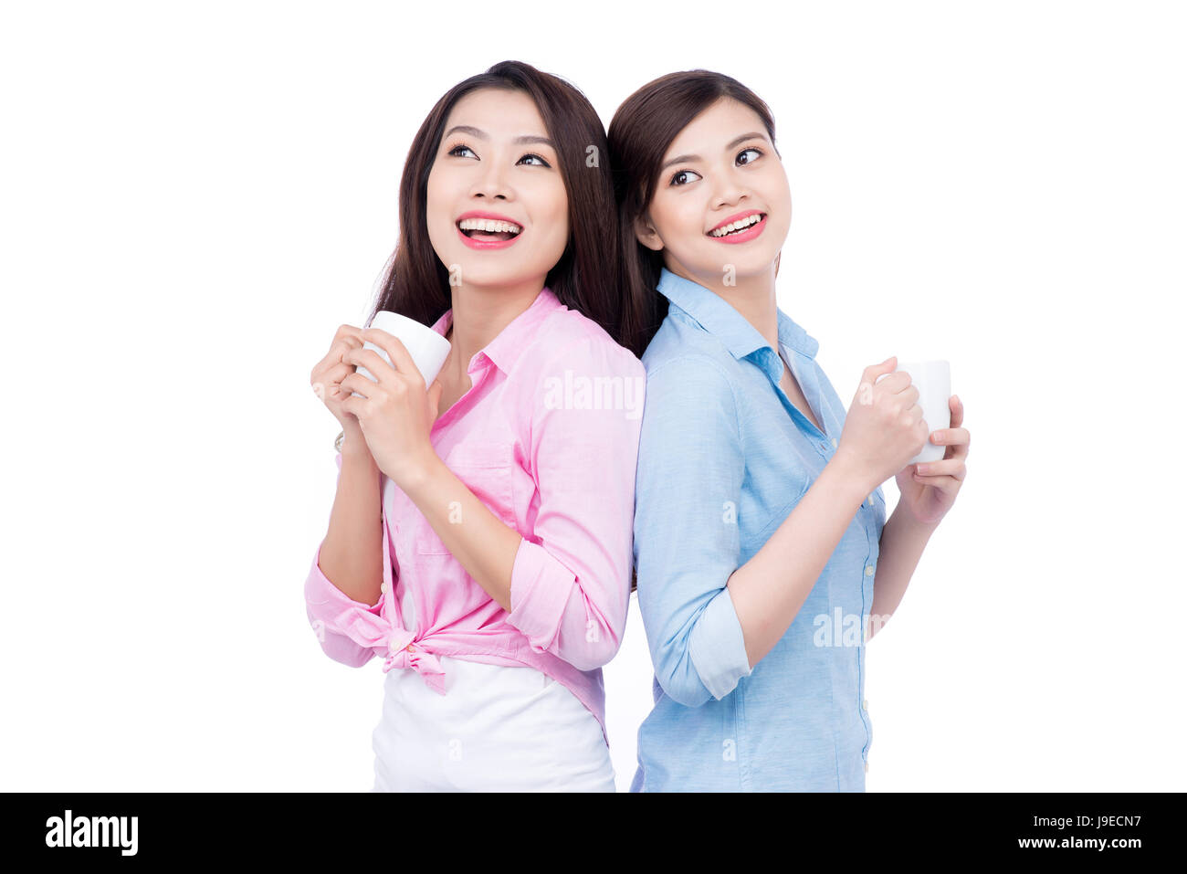 Cheerful asian female friends holding tasses à café bénéficiant d'une conversation Banque D'Images