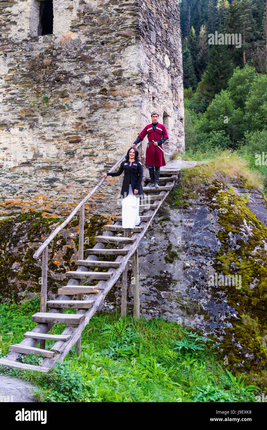 Couple en costume traditionnel géorgien en ordre décroissant des escaliers de la tour de l'amour, pour un usage éditorial uniquement, Ushguli, région de Svaneti, Géorgie Banque D'Images