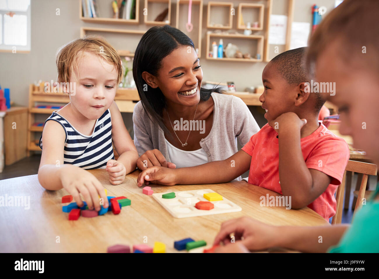 Les élèves et enseignants à l'aide de formes en bois dans l'école Montessori Banque D'Images