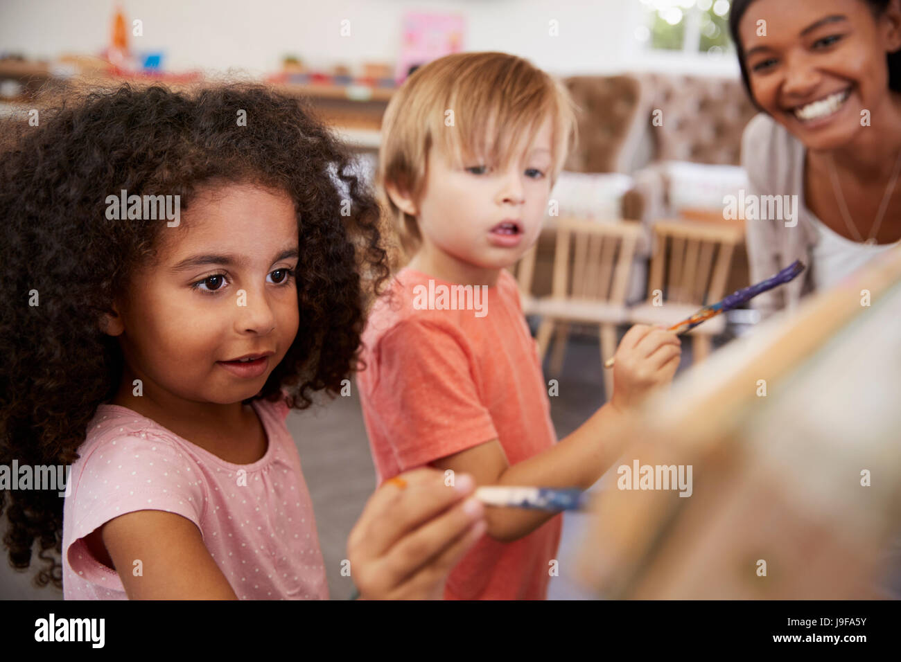 Professeur à l'École Montessori d'aider les enfants dans la classe d'Art Banque D'Images