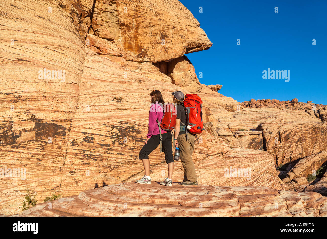 Couple avec le matériel d'escalade rock admirer lumière dorée au coucher du soleil un tRed Rock Canyon National Conservation Area, qui est à environ 20 miles de Las Vegas Banque D'Images