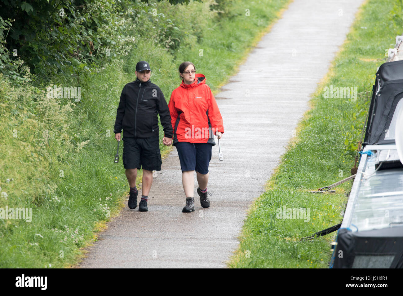 Un couple en train de marcher en short et manteaux de pluie le long d'un canal toe chemin sur un jour de pluie le long du Canal, l'Union shopshire Sandbach Banque D'Images