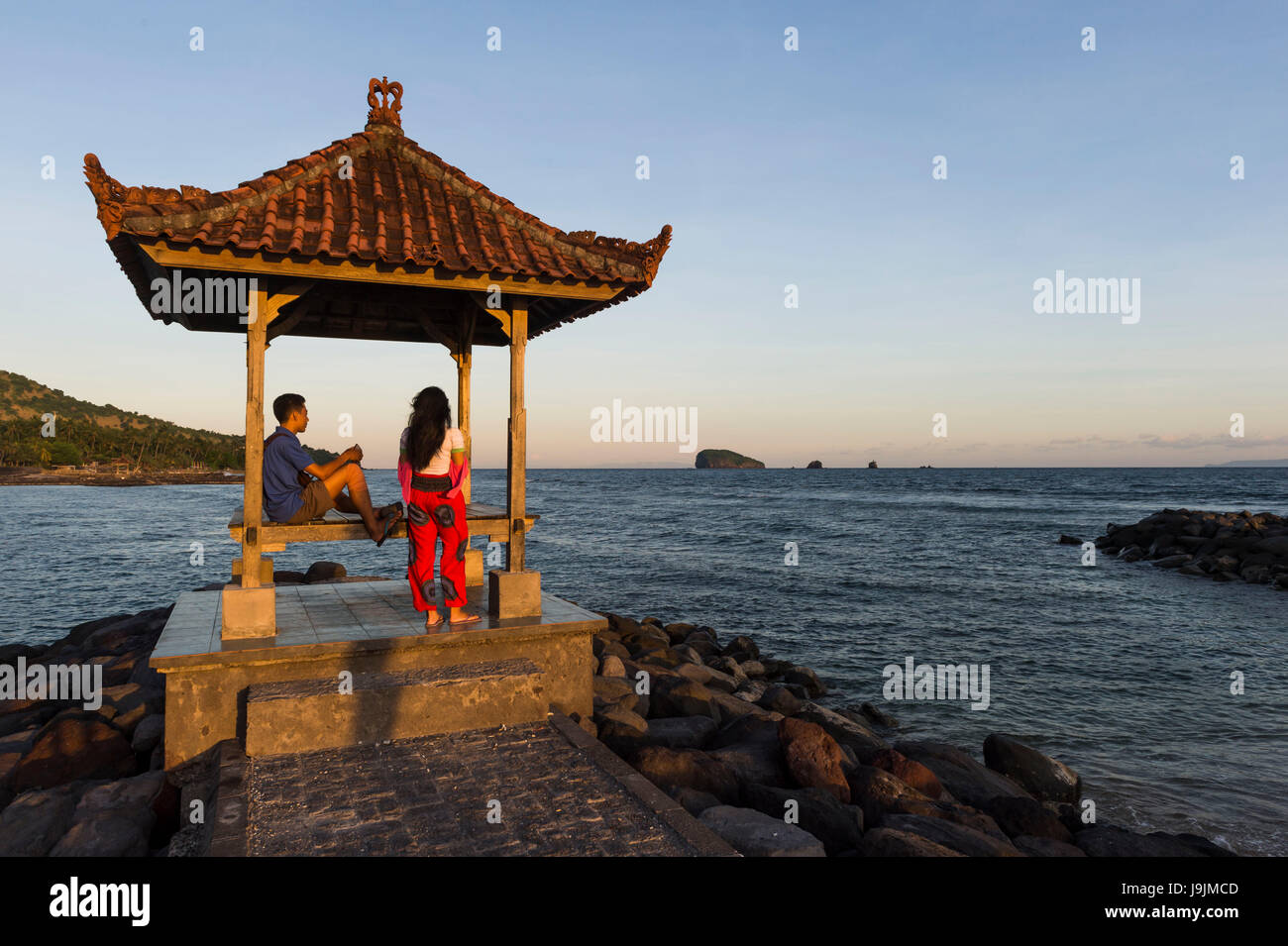 Jeune couple par la mer en face de Candi Dasa avec Gili Mimpang Gili Tepekong et Banque D'Images
