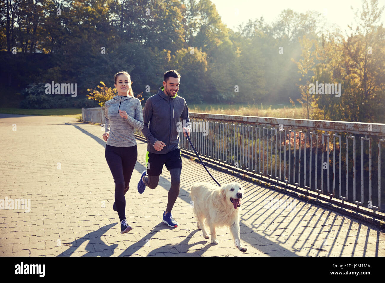 Heureux couple avec chien qui court à l'extérieur Banque D'Images