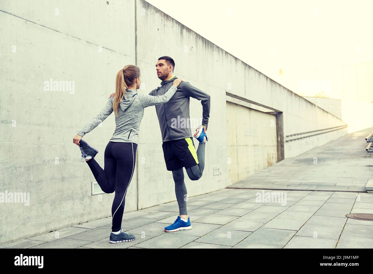 Couple de sportifs qui s'étend de la jambe on city street Banque D'Images