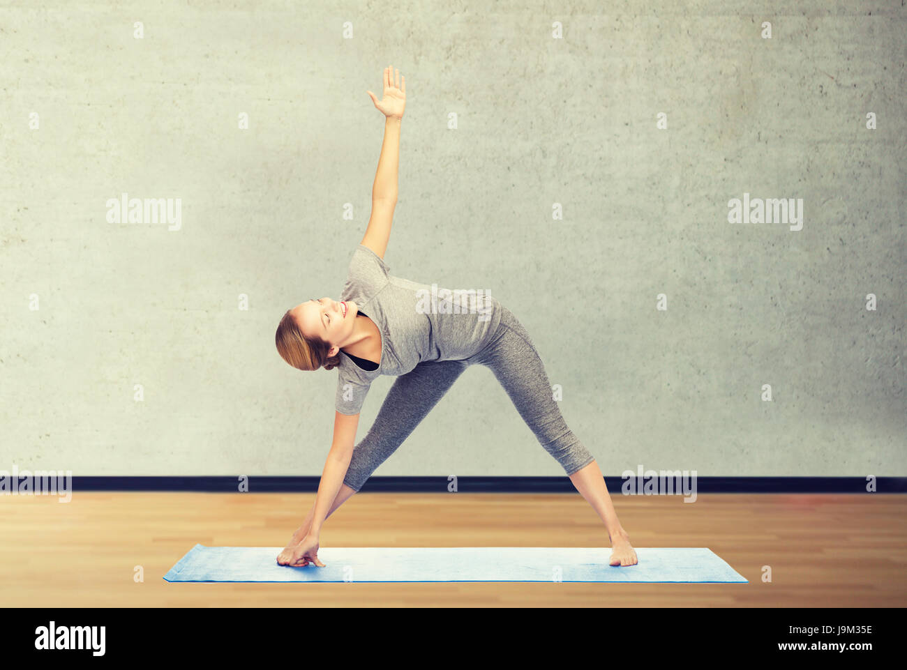 Femme faisant triangle yoga posent sur mat Banque D'Images