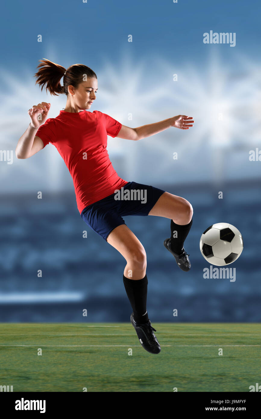 Portrait of female soccer player kicking ball stade intérieur Banque D'Images
