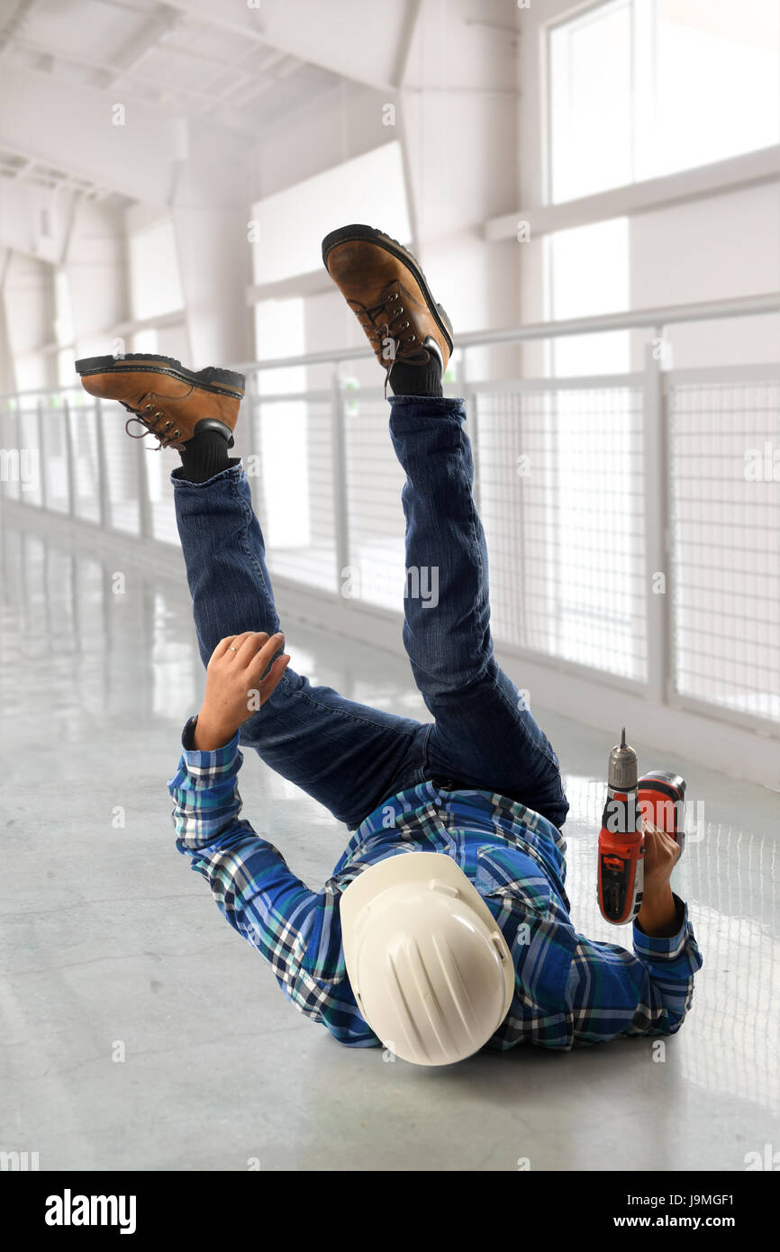 Worker holding tournevis sans fil tomber sur le plancher à l'intérieur du bâtiment Banque D'Images