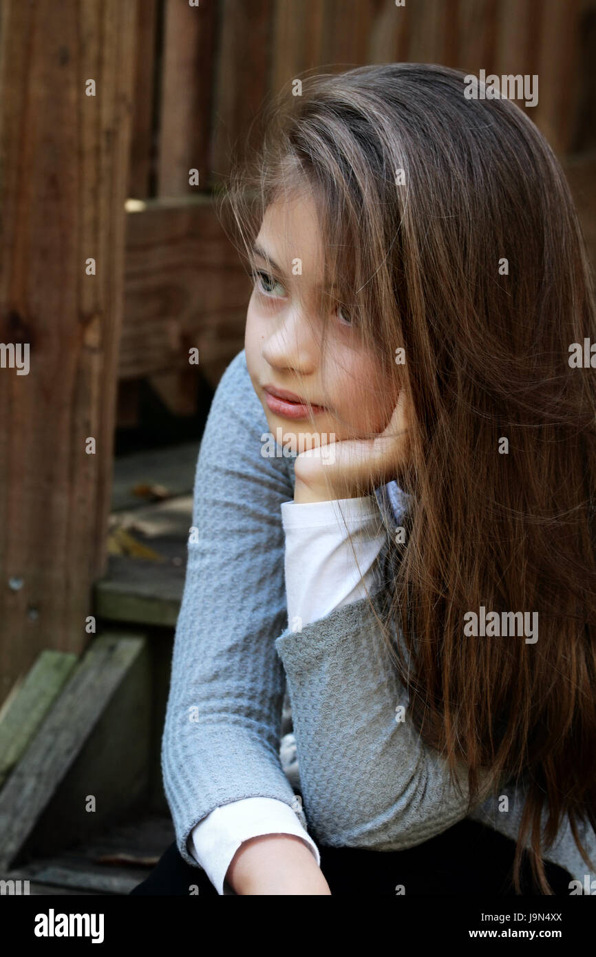 Jeune fille assise sur les marches de la véranda avec de longs cheveux tombant autour de son visage. L'extrême profondeur de champ. Banque D'Images