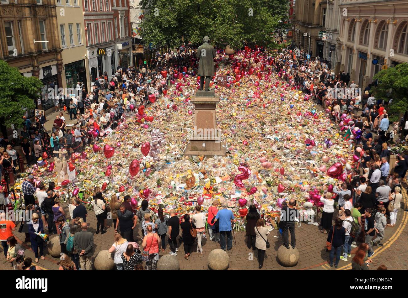 Les gens regardent les fleurs et hommages à gauche dans St Ann's Square à Manchester Manchester Arena suite à l'attaque terroriste. Banque D'Images