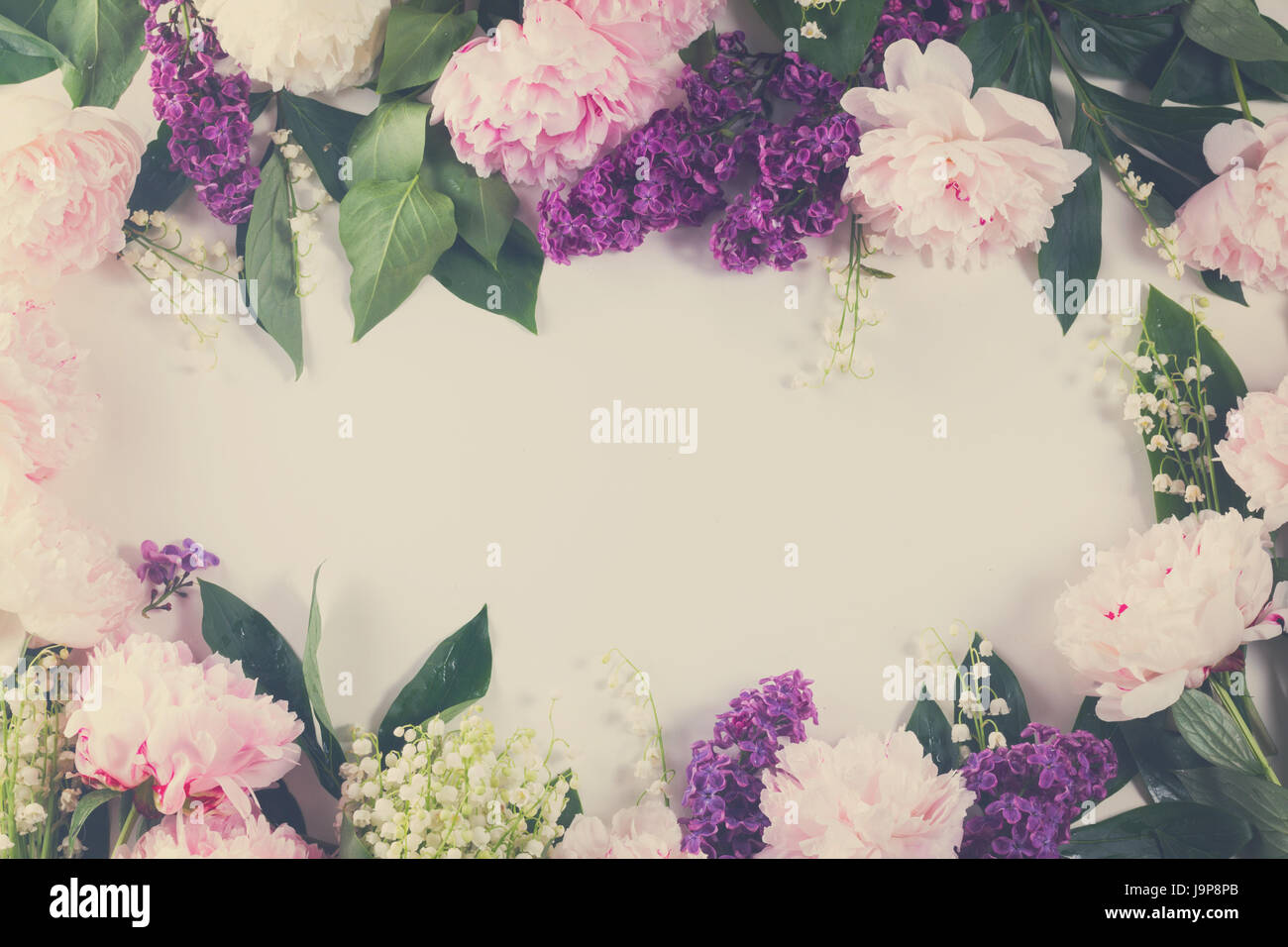 Frontières Floral de fleurs fraîches - lilas, pivoines et lilly du walley flowers frame sur fond blanc avec copie espace, tons rétro Banque D'Images