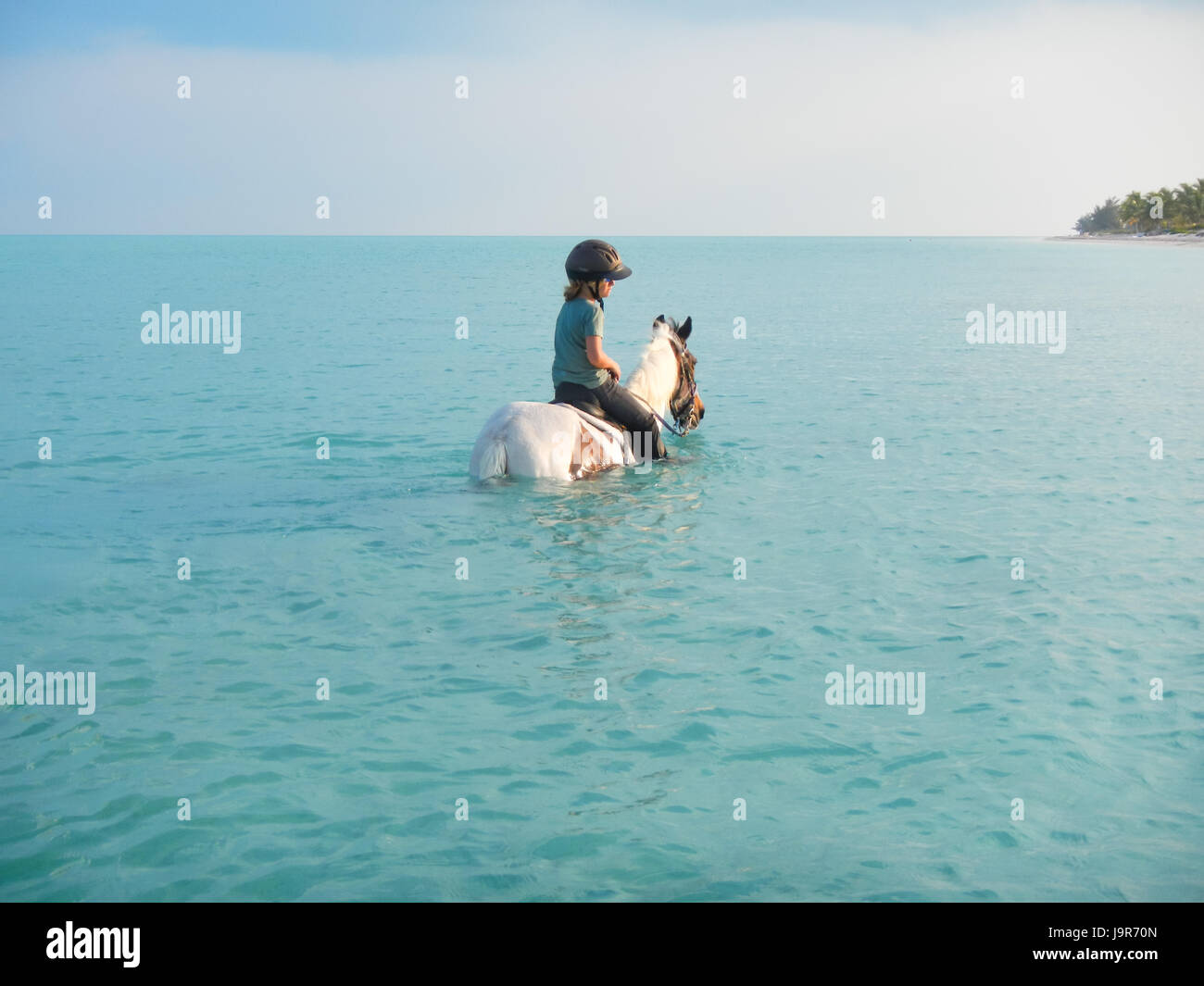 Les enfants de l'équitation dans les eaux de l'océan sur l'île de la mer des Caraïbes Turks & Caicos - vacances en famille Banque D'Images