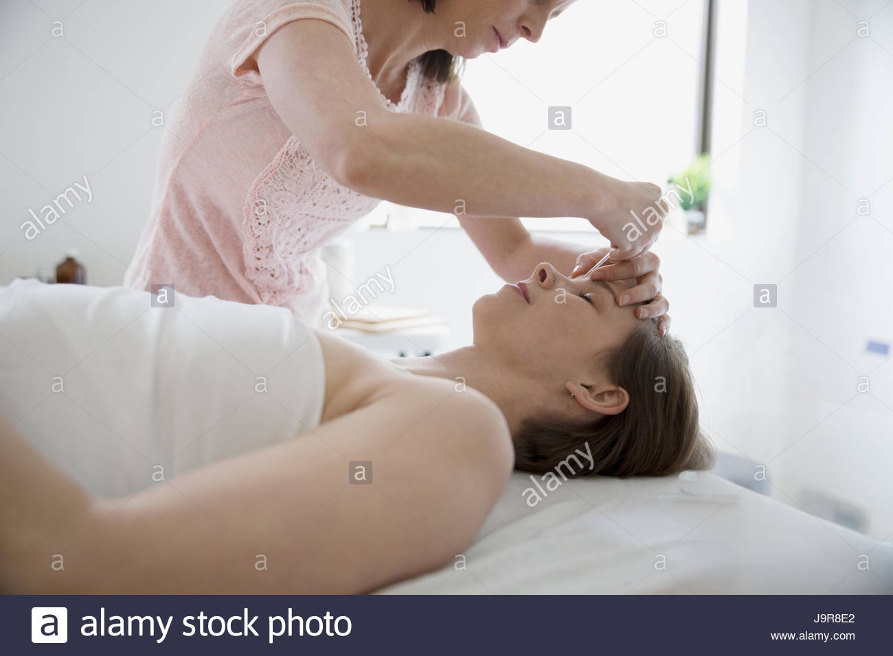 L'insertion d'aiguille dans l'acupuncteur femelle front of woman on massage table Banque D'Images