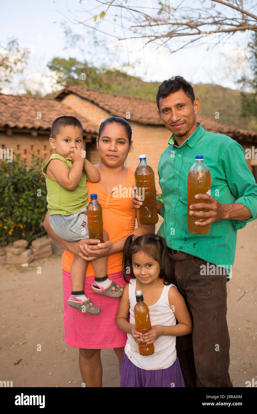 Une famille d'éleveurs d'abeilles bouteilles de hold-fraîchement récolté le miel dans Léon, Ministère du Nicaragua. Banque D'Images