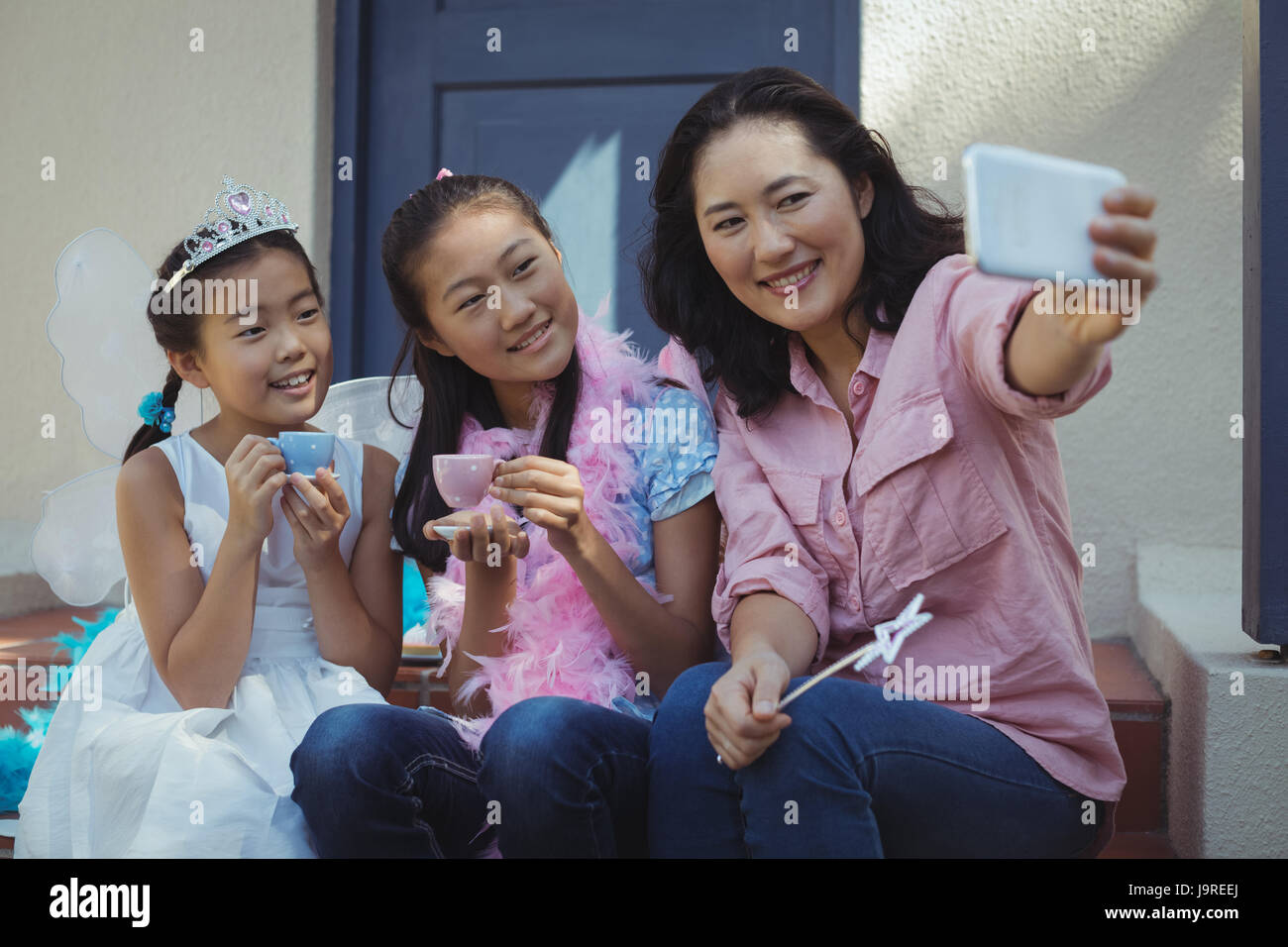 Frères et sœurs en costume de fée et mère de prendre un téléphone mobile sur selfies at home Banque D'Images