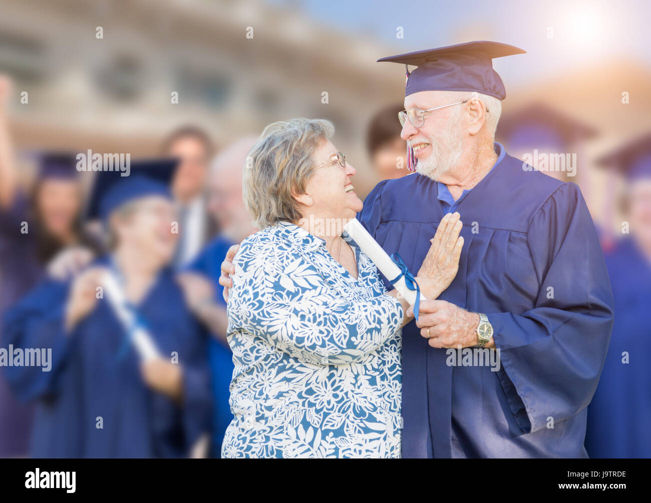 Mâle adulte Senior à Cap and Gown être félicité par femme à une cérémonie de remise de diplômes. Banque D'Images