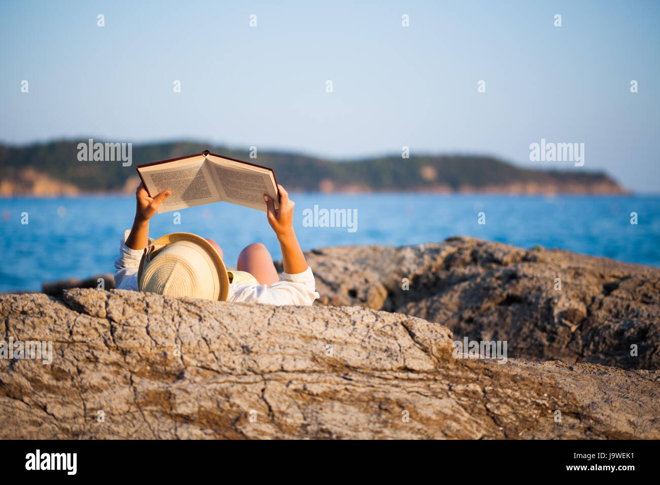 Femme lisant un livre sur la mer Banque D'Images