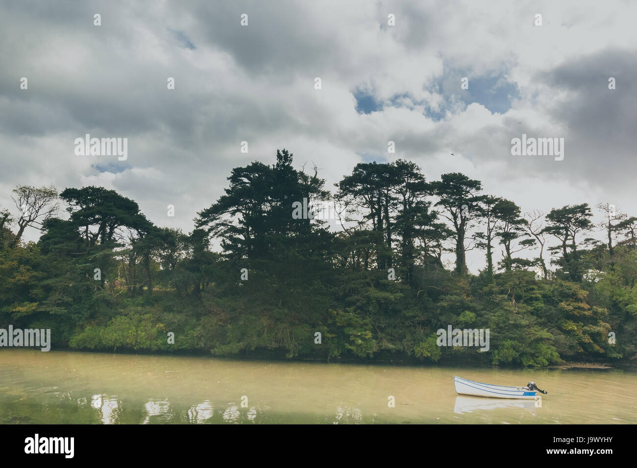 Le décor d'un lac avec les forêts, ciel bleu avec un bateau de pêche dans l'avant-plan. Banque D'Images