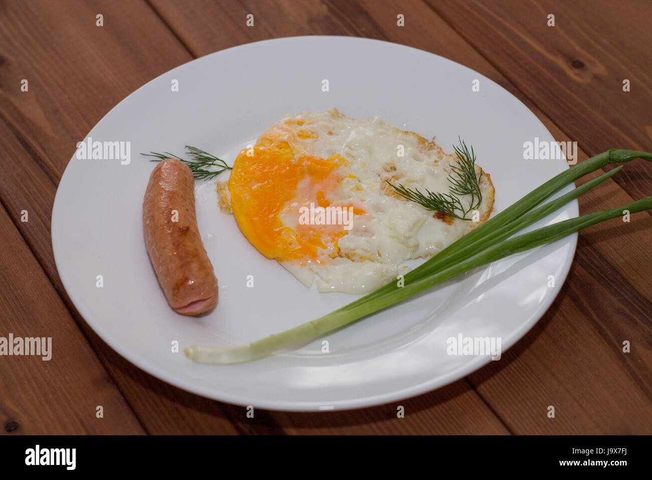 Le petit-déjeuner sur une assiette. Oeufs au plat avec des saucisses et des oignons verts. Banque D'Images