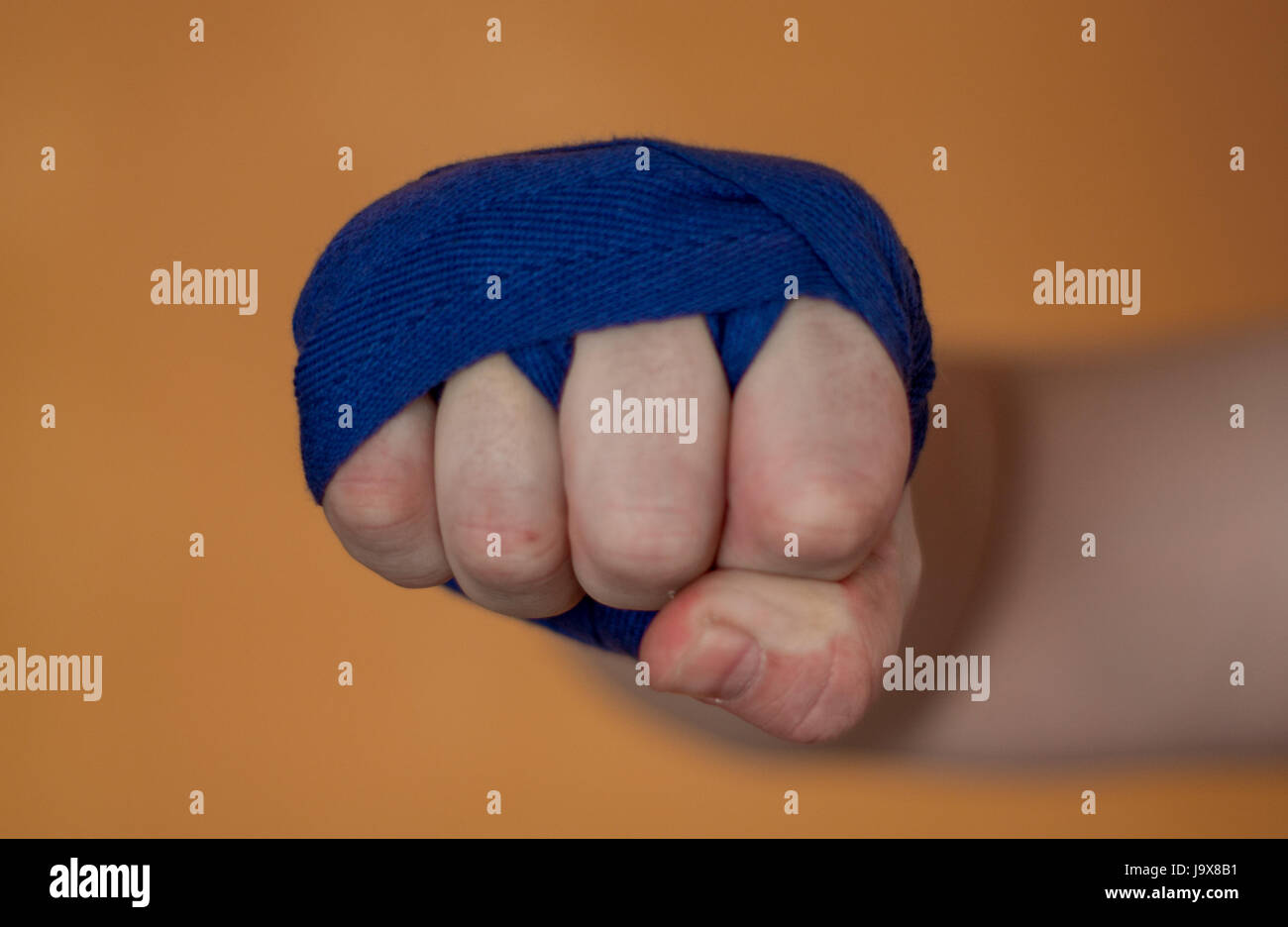 Poing de Boxer sur un fond orange punch avec bandage d'appui de poignet. Banque D'Images