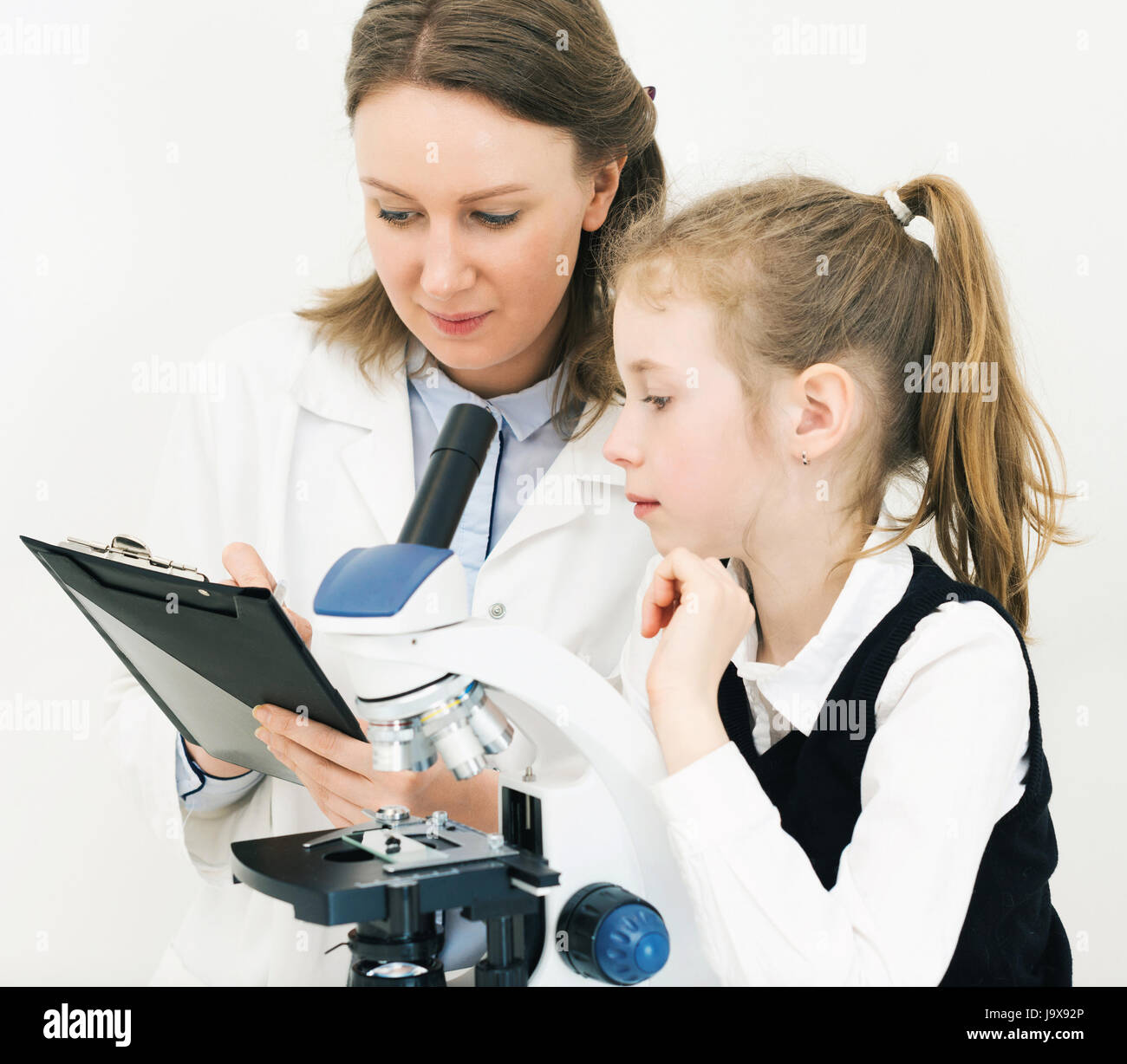 Femme et petite fille using microscope in laboratory. Banque D'Images