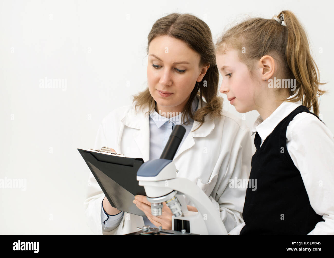 Femme et petite fille using microscope in laboratory. Banque D'Images
