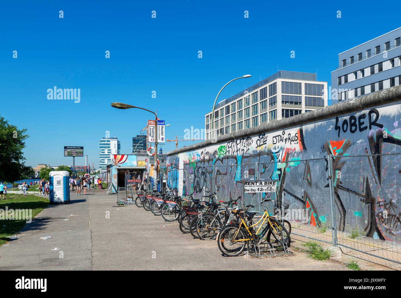 Location de vélo par une section du mur de Berlin à l'East Side Gallery, Friedrichshain-Kreuzberg, Berlin, Allemagne Banque D'Images