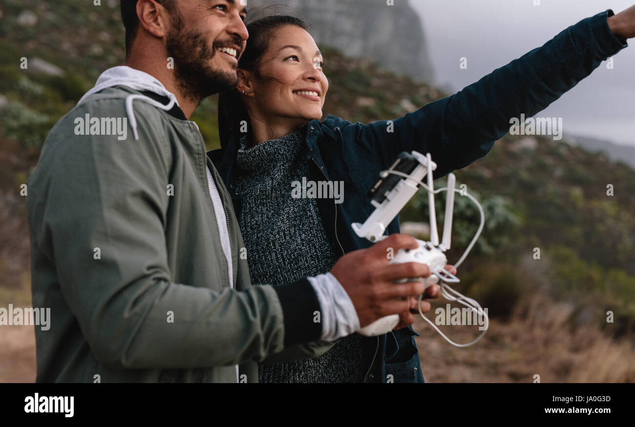 Happy young woman outdoors with man holding d'une télécommande pour l'exploitation de drones et de la femme en pointant à l'écart. L'homme et la femme battant dron Banque D'Images