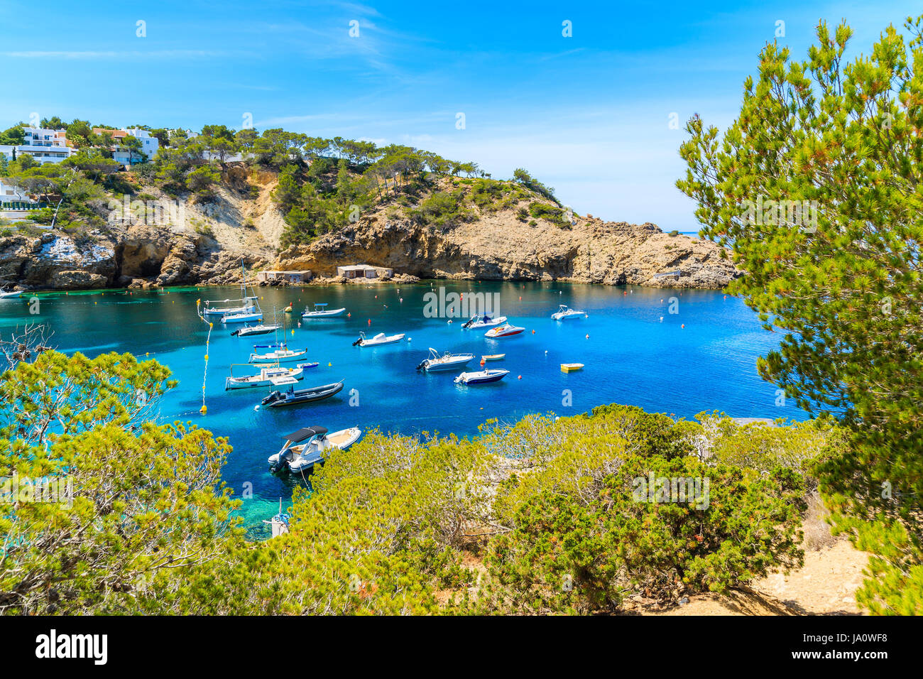 La pêche et la voile des bateaux sur la mer bleue de l'eau dans la baie de Cala Vadella, Ibiza island, Espagne Banque D'Images