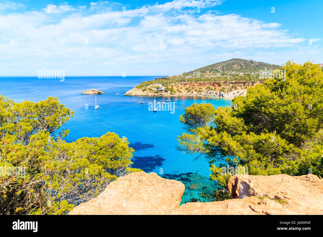 Vue sur la baie de Cala d'Hort avec belle mer bleu azur de l'eau et des pins sur falaise rochers, l'île d'Ibiza, Espagne Banque D'Images