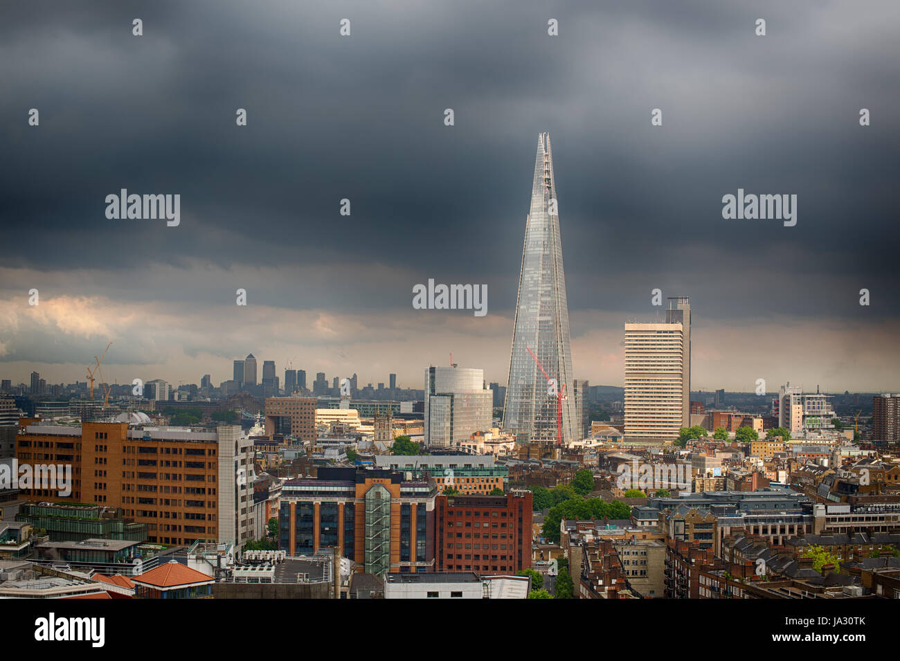 London city skyline avec une lumière vive sur les bâtiments et un ciel d'orage sombre derrière. Banque D'Images