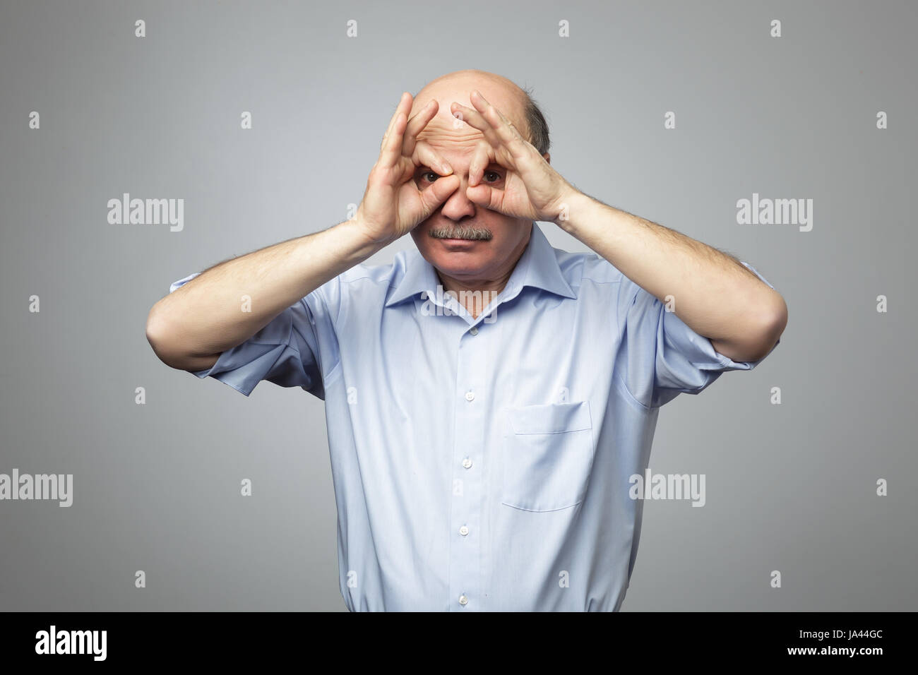 Old man holding doigts près des yeux comme lunettes : comme masque de super héros ou owl Banque D'Images