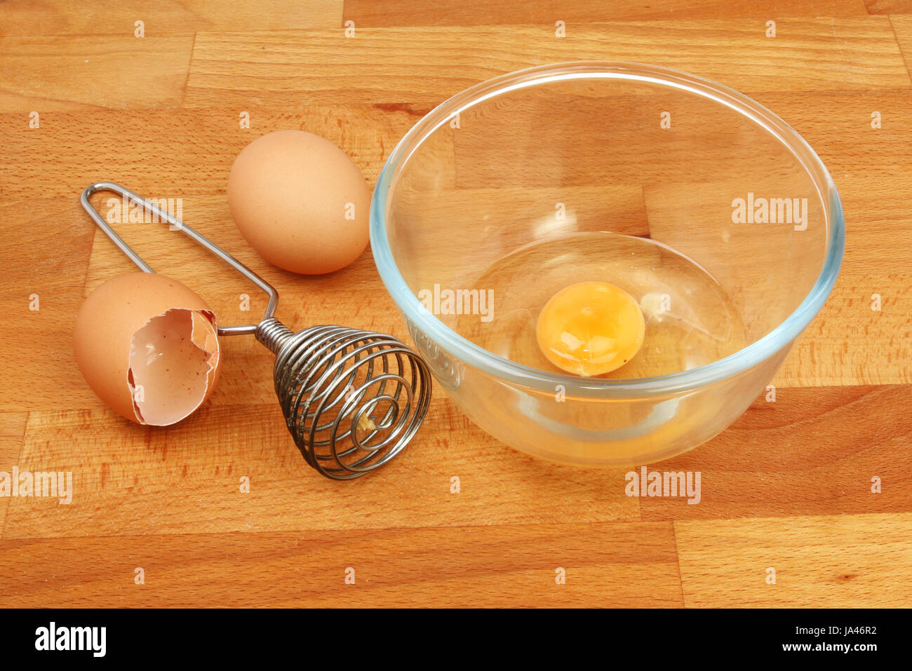 Bol et fouetter les oeufs sur un plan de travail de cuisine en bois Banque D'Images
