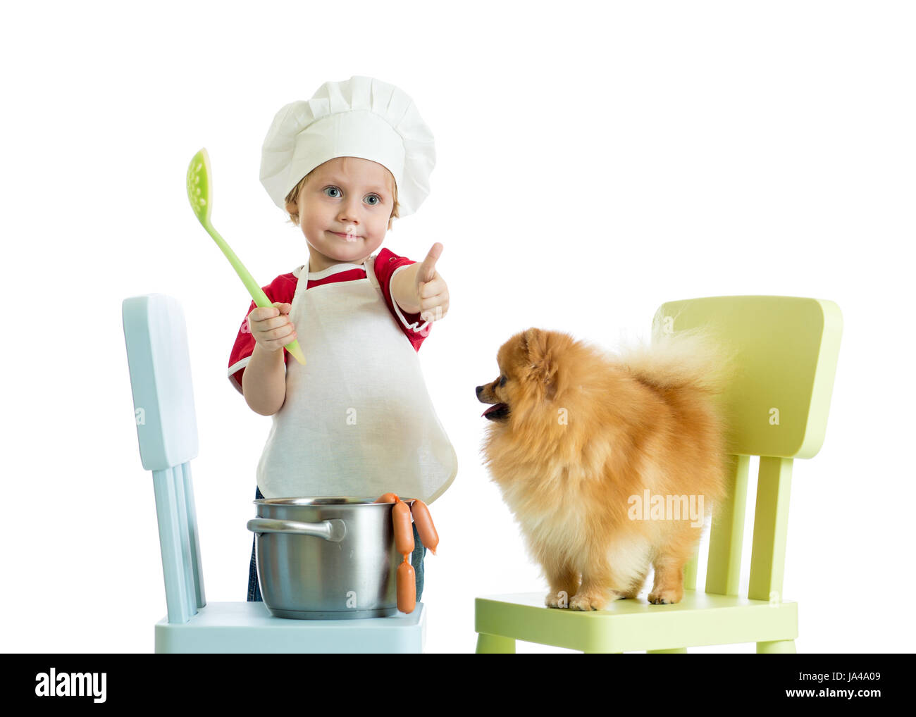 Kid Garçon jouant chef avec chien. Portée des enfants rss cook chiot Spitz. Banque D'Images