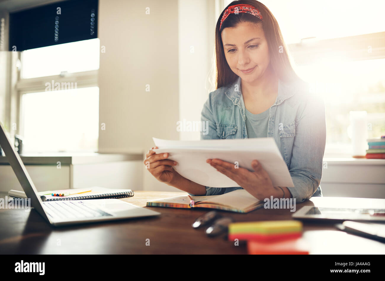 Cheerful young businesswoman sitting travail avec des documents sur le lieu de travail en bureau. Banque D'Images