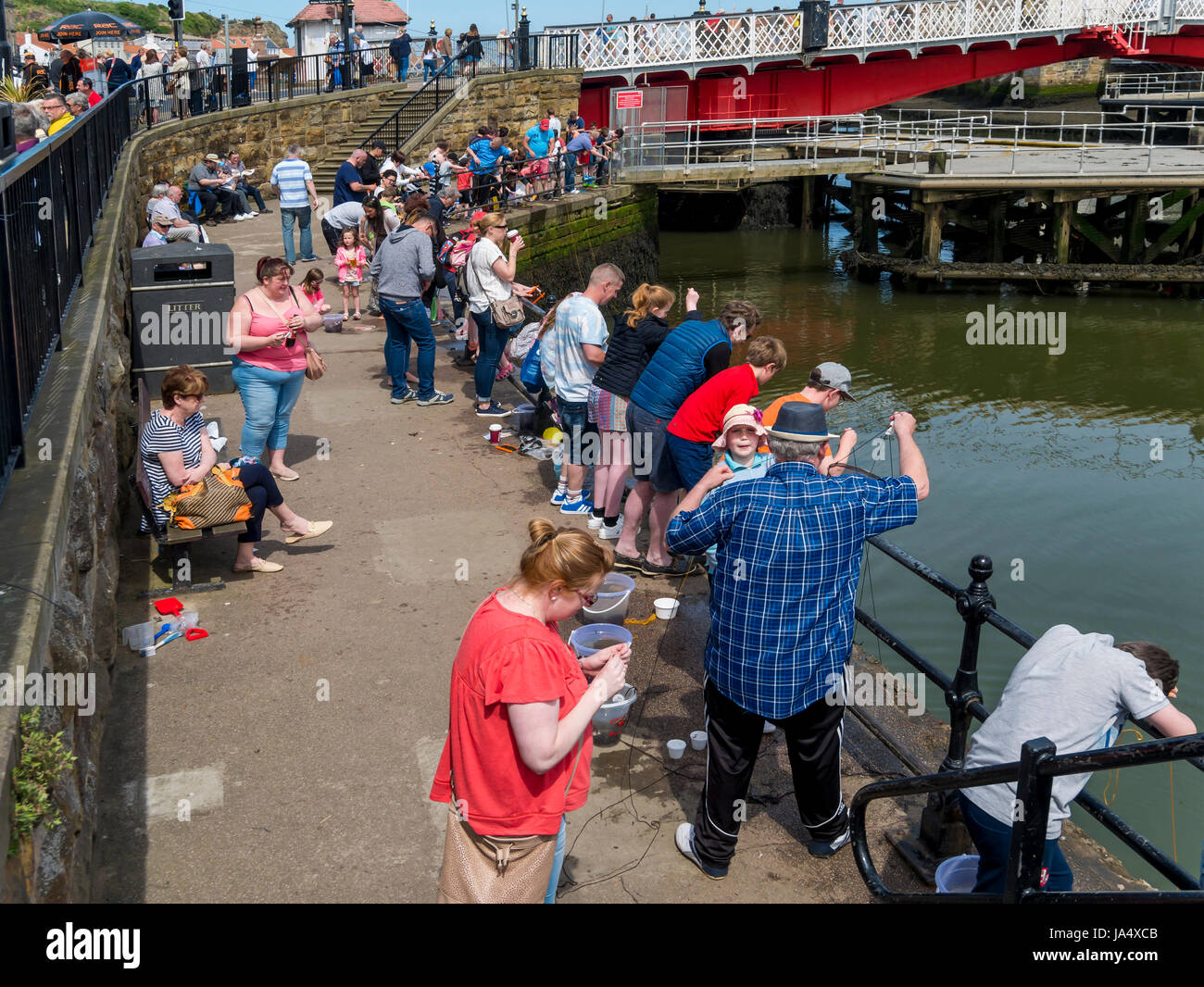 Les vacanciers au printemps la pêche de crabes par le pont dans le port de Whitby, North Yorkshire Angleterre UK Banque D'Images